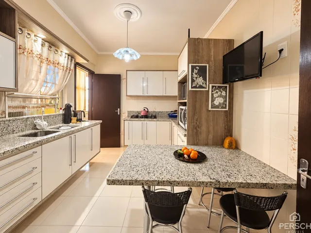 Foto de uma cozinha com bancadas de granito e mesa de jantar em um apartamento.