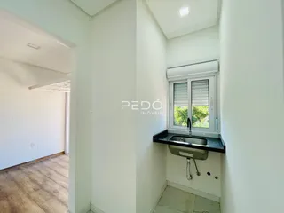 Interior de um ambiente com parede branca e piso de madeira.