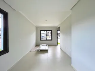 Interior de um corredor longo com paredes brancas e piso claro.