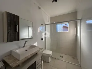 Banheiro moderno com box de vidro e revestimentos claros.