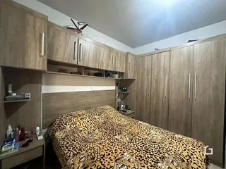 Quarto com armários em madeira e cabeceira de madeira.