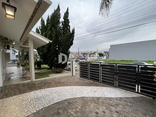 Vista da fachada de uma propriedade com portão preto e calçada de pedras.