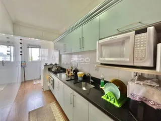 Cozinha moderna com armários cinzas e bancadas escuras em um imóvel no Brasil.