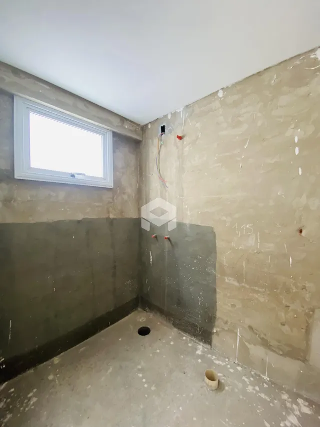 Foto de um cômodo interno com paredes de concreto cru e janela.