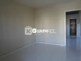 Vista interna de um ambiente com paredes brancas e piso claro.