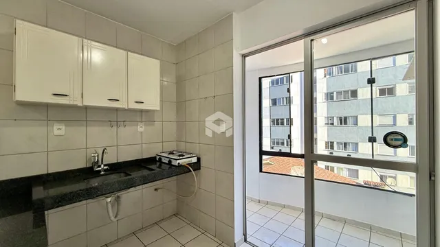 Cozinha com armários brancos e revestimento de cerâmica.
