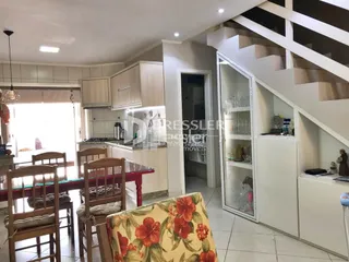Interior de uma sala com cozinha e escadaria em um imóvel.