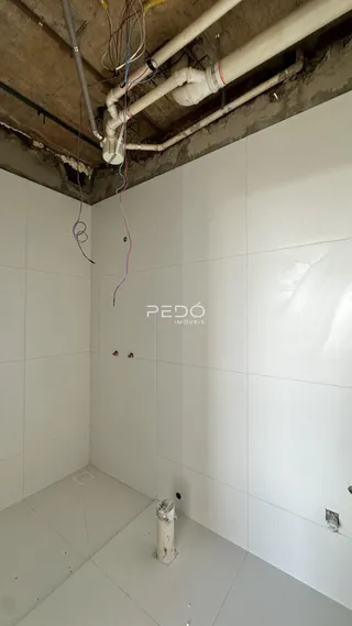 Foto de uma área interna em construção com paredes brancas e teto exposto.