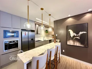 Cozinha moderna com bancada em mármore e iluminação pendente.