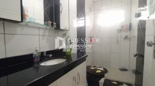 Foto de um banheiro com revestimento cerâmico branco.