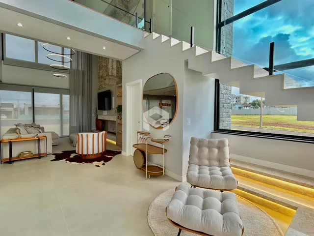 Sala de estar com grandes janelas e escadaria em um imóvel em Lajeado.
