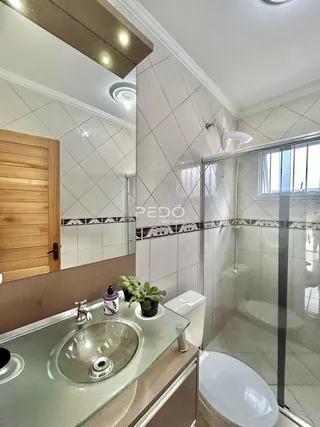 Foto de um banheiro com revestimento cerâmico e box de vidro.