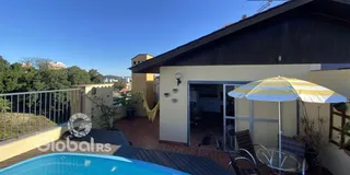 Vista externa de uma casa com piscina e varanda.