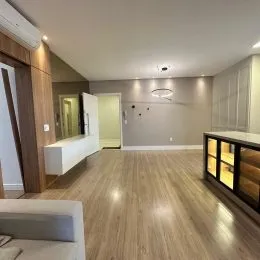 Sala de estar com piso de madeira clara e iluminação interna.