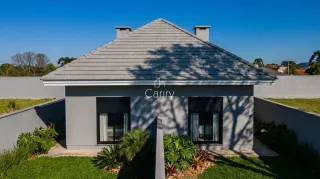 Fachada externa de uma residência com telhado de telhas cinzas e paisagismo verde.