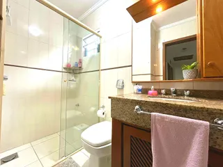 Foto de um banheiro com box de vidro e revestimento cerâmico.