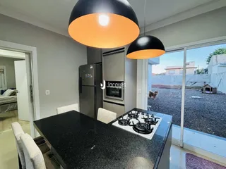 Uma cozinha moderna com ilha escura e vista para o quintal.