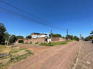 Vista externa de uma propriedade com muro de tijolos e estrada de terra.