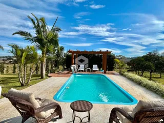 Piscina externa com paisagem tropical e vegetação ao redor.