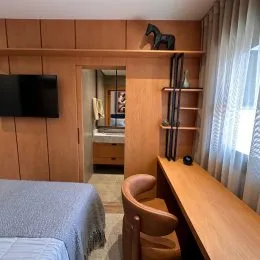 Quarto com painéis de madeira e cortinas claras.