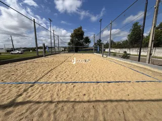 Uma área externa de areia cercada por uma cerca de arame.