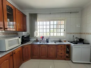A cozinha apresenta armários de madeira e uma grande janela.