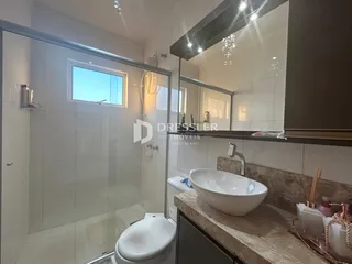 Foto de um banheiro com box de vidro e louças brancas.