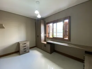Quarto com parede clara e janela de madeira no interior da residência.