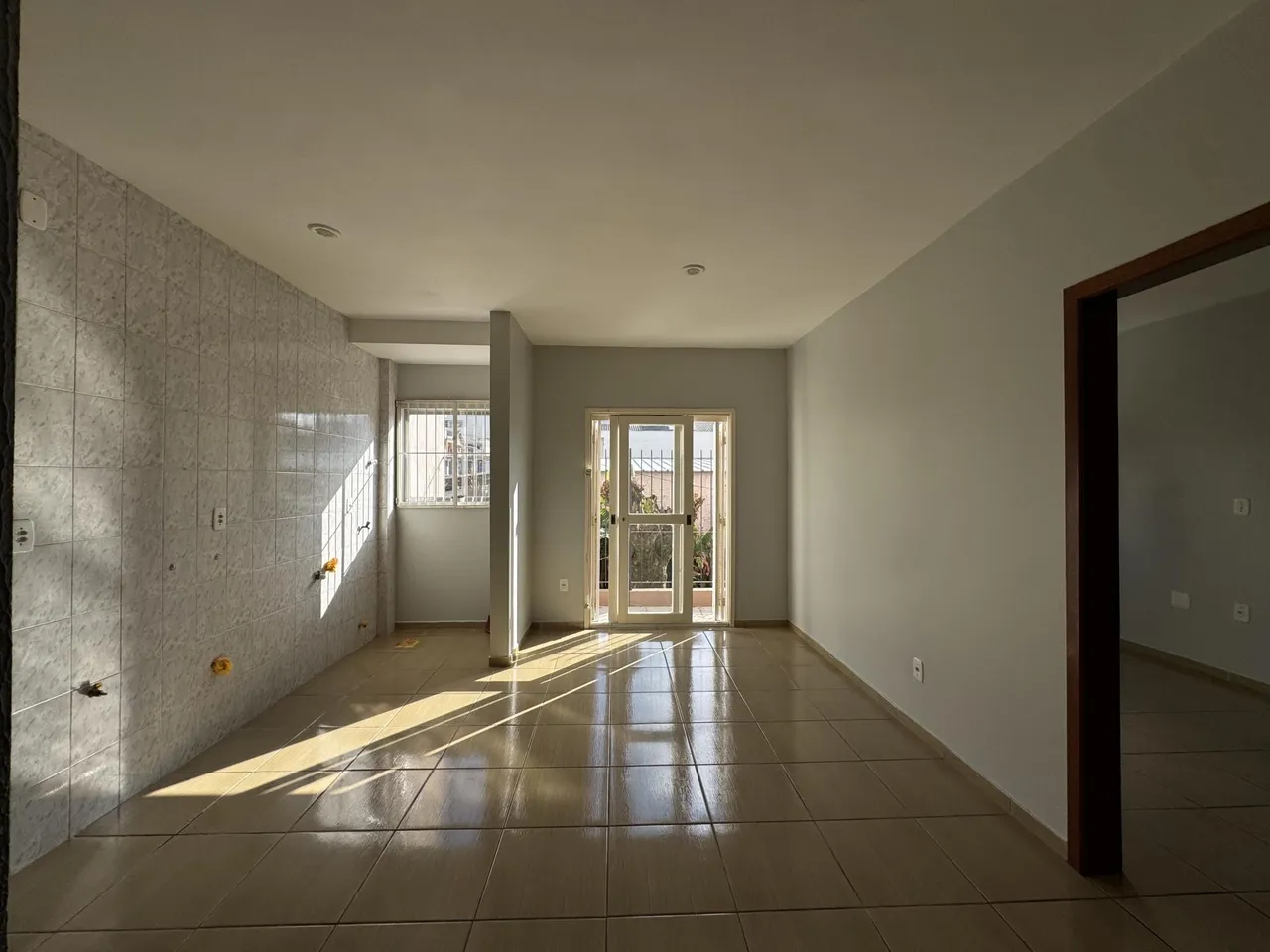 Hall de entrada com piso de cerâmica e paredes brancas.