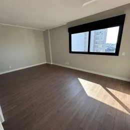 Ambiente interno com piso de madeira e janela grande.