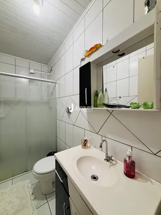 Foto de um banheiro com revestimento cerâmico branco e box de vidro.