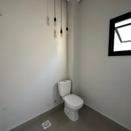Foto de uma parede branca com um vaso sanitário em um ambiente interno.