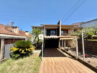Foto da fachada de uma residência em Lajeado, Brasil, mostrando a entrada e um pátio de madeira.