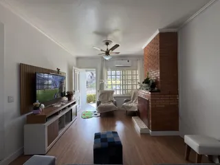 Sala de estar com piso de madeira e parede de tijolos na residência.