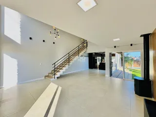 Sala de estar ampla com piso de cerâmica e escadaria.
