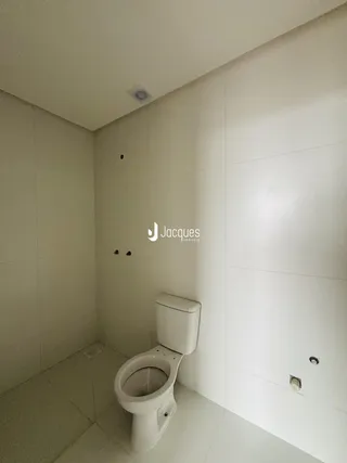 Um banheiro com paredes brancas e piso claro.