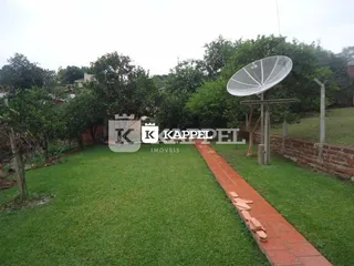 Vista externa mostrando um gramado e um caminho de tijolos em uma área verde.