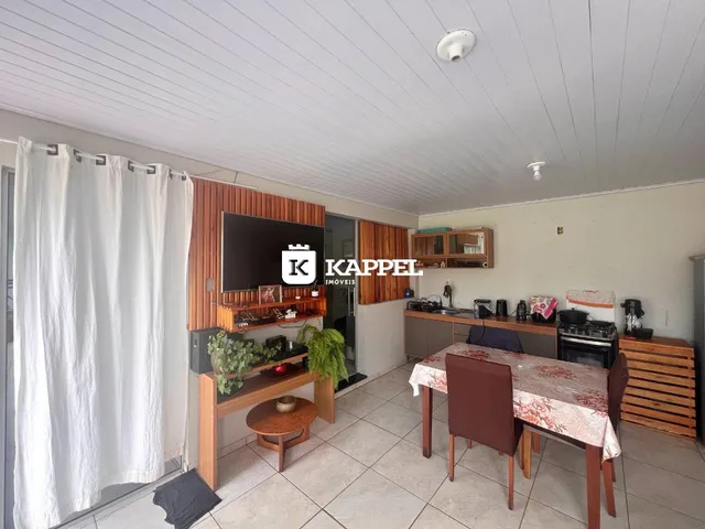 Sala de estar com televisão e mesa de jantar em um ambiente claro.