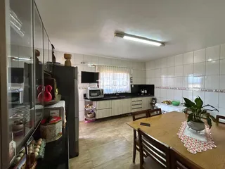 Imagem de uma cozinha com armários e mesa de jantar em um imóvel no Brasil.