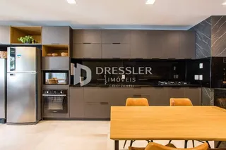 Vista da cozinha moderna com armários escuros e bancadas claras.