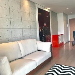 Uma sala de estar com sofá branco e piso de madeira polida.