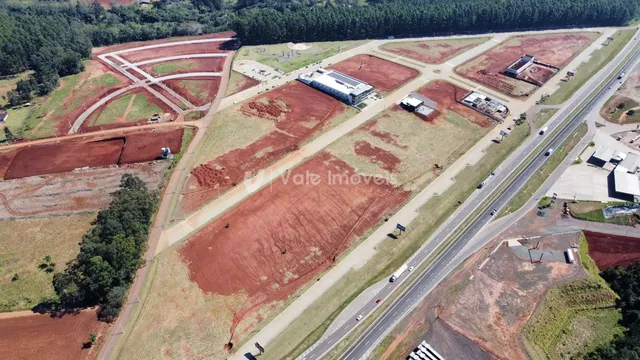 Vista aérea de um terreno aberto com áreas de terra vermelha e vegetação.