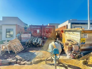 Vista externa de um terreno em construção com materiais de construção expostos.
