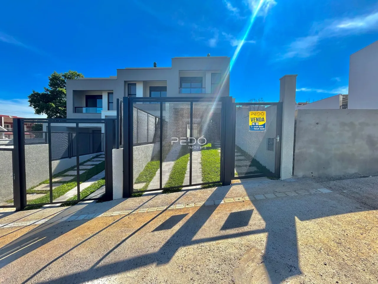 Fachada moderna de uma residência com portão de ferro e concreto.