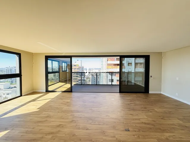 Sala de estar com piso de madeira e portas de vidro que dão para a vista.