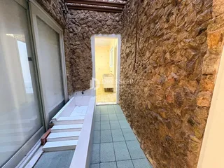 Parede de pedra rústica com piso de cerâmica em uma área de transição.