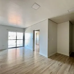 Sala de estar com piso de madeira clara e porta de vidro.