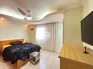 Quarto com cama de madeira e janela com cortinas brancas.