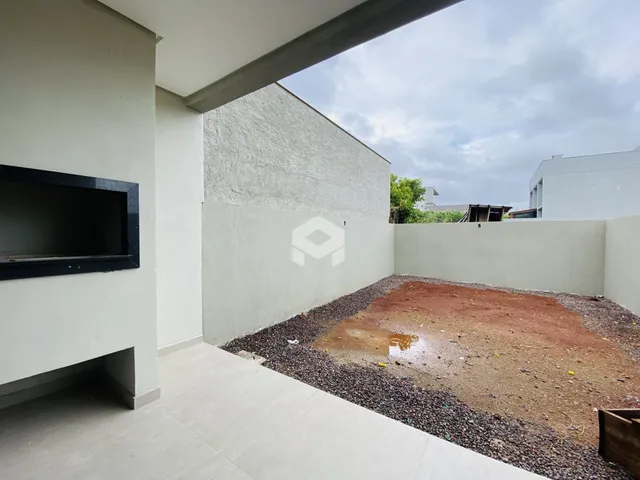 Vista da fachada de uma propriedade com parede branca e área externa de terra e cascalho.