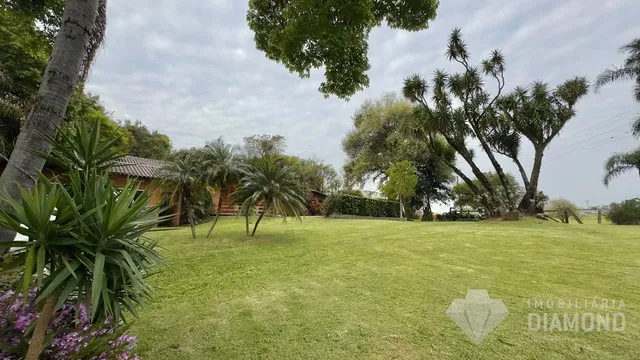 Gramado verde extenso com árvores ao fundo em uma propriedade.